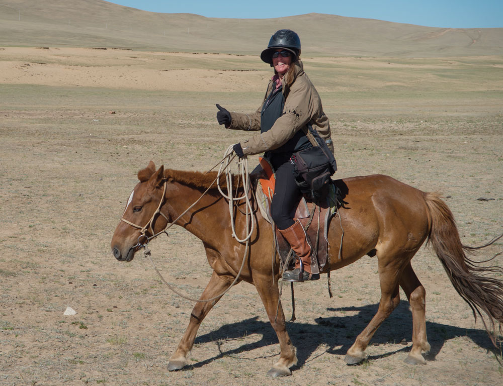 Photographer Shawn Hamilton riding a horse in Mongolia