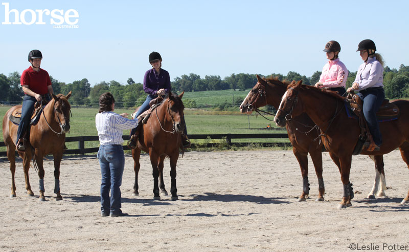 A group of adults taking a riding lessons as a trainer instructs them on their horses