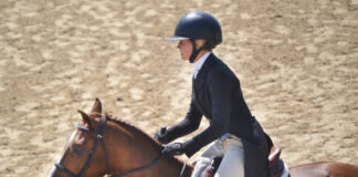 A girl riding a horse and wearing proper attire, including a riding helmet