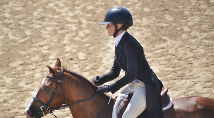 A girl riding a horse and wearing proper attire, including a riding helmet