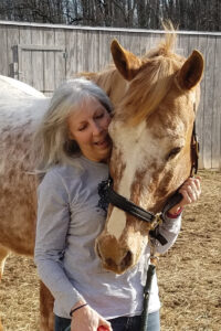 A senior woman happily interacts with a senior Appaloosa horse she adopted