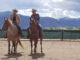 Julie Goodnight and her husband, Rich Moorhead, on horses with a mountain backdrop