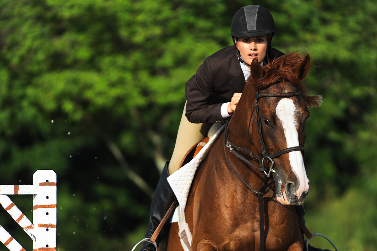 An equestrian jumps her horse, using riding advice for her best performance possible
