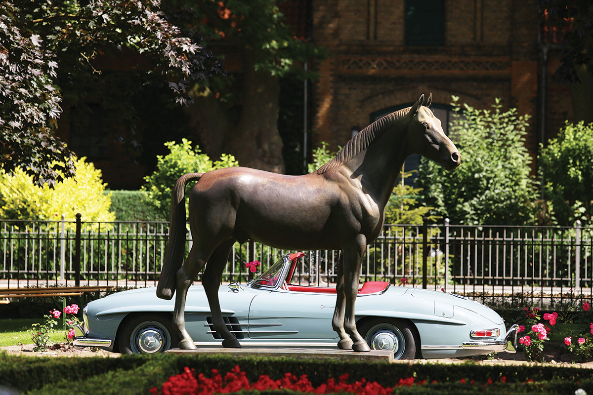 A horse statue next to a classic Mercedes.