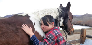 A woman hugs a horse at an equine retreat to improve equestrian wellness and fitness