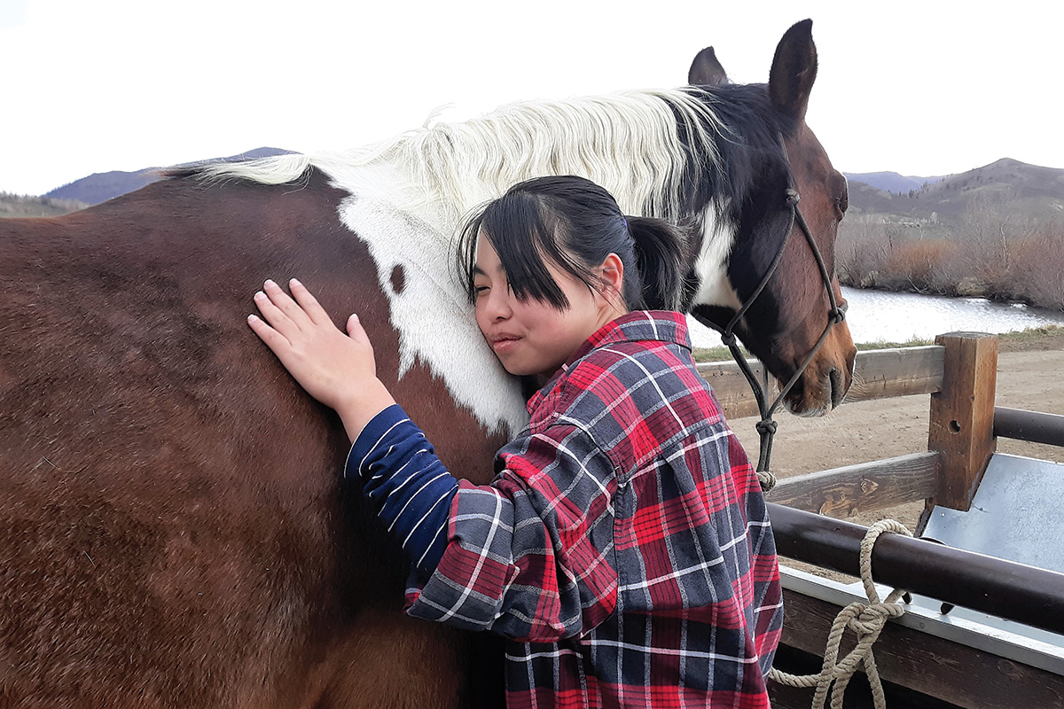 A woman hugs a horse at an equine retreat to improve equestrian wellness and fitness