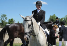 A horse owner riding her horse at a dressage show