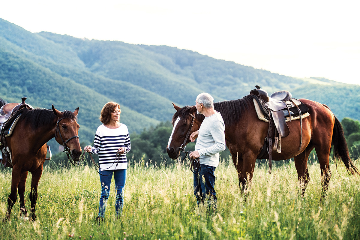 An older couple taking a break on a trail ride.