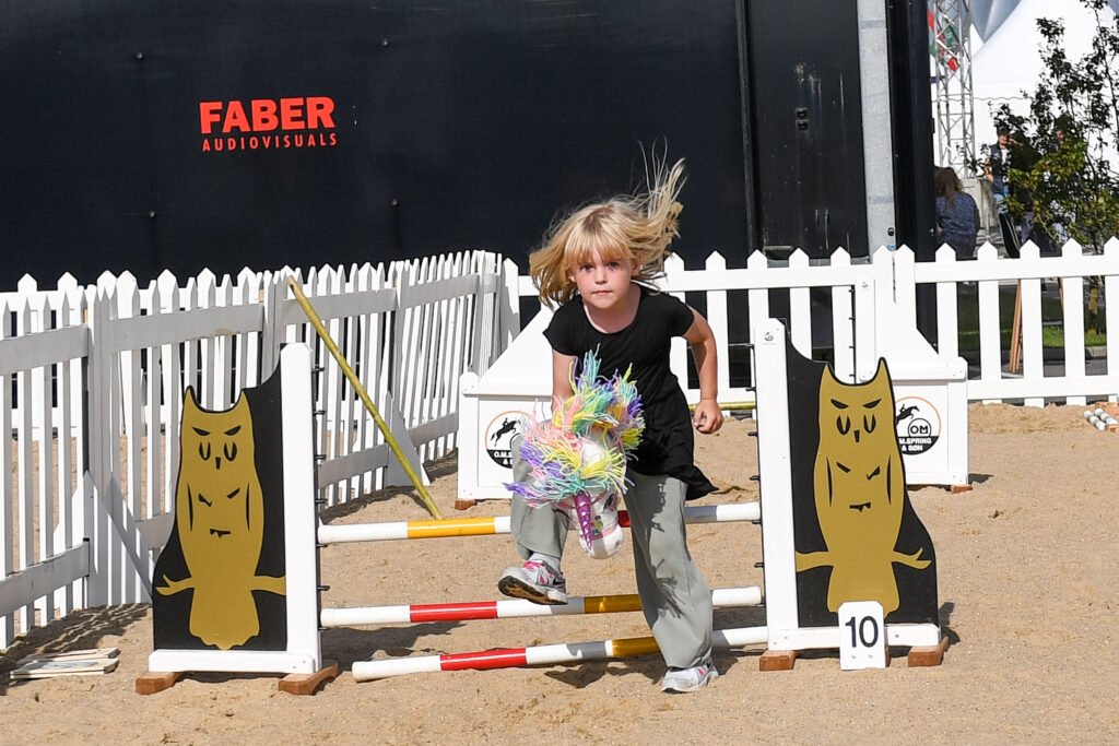 A young Danish girl jumps her stick horse around the Panduro Hobby Horse jumper course in the children’s area at the 2022 FEI World Championships in Herning