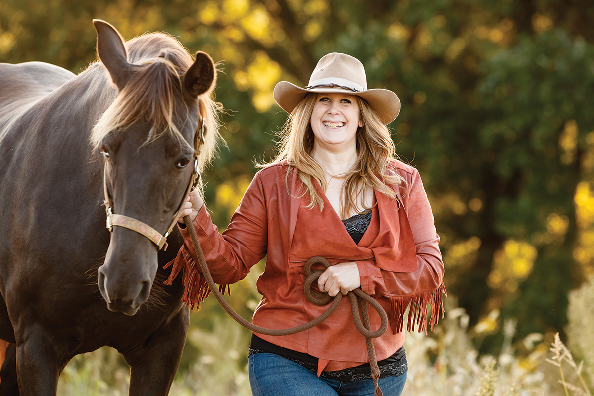 A woman in a fringe jacket holds a horse
