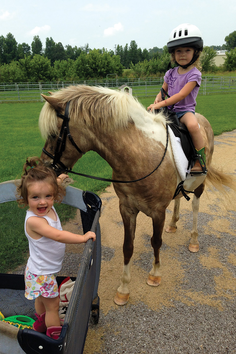 Two babies at the barn with a pony