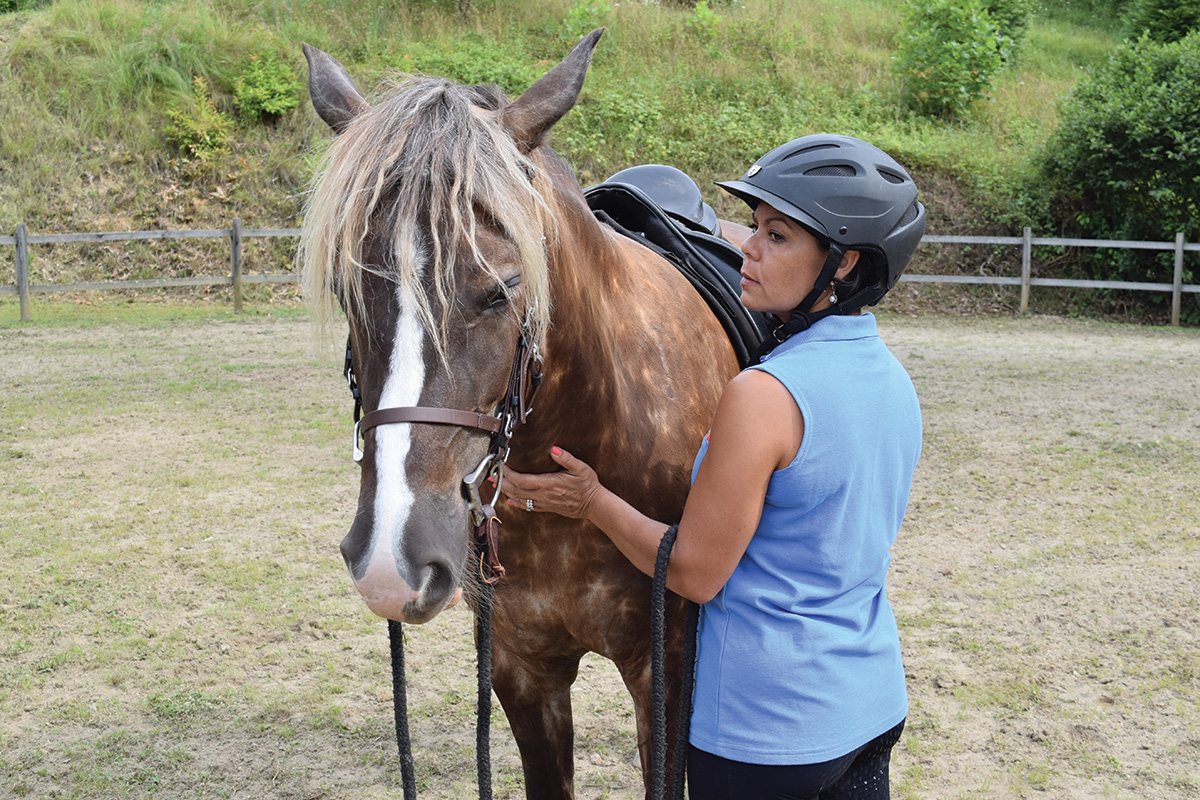 A woman pats a horse at an equine retreat to improve equestrian wellness and fitness