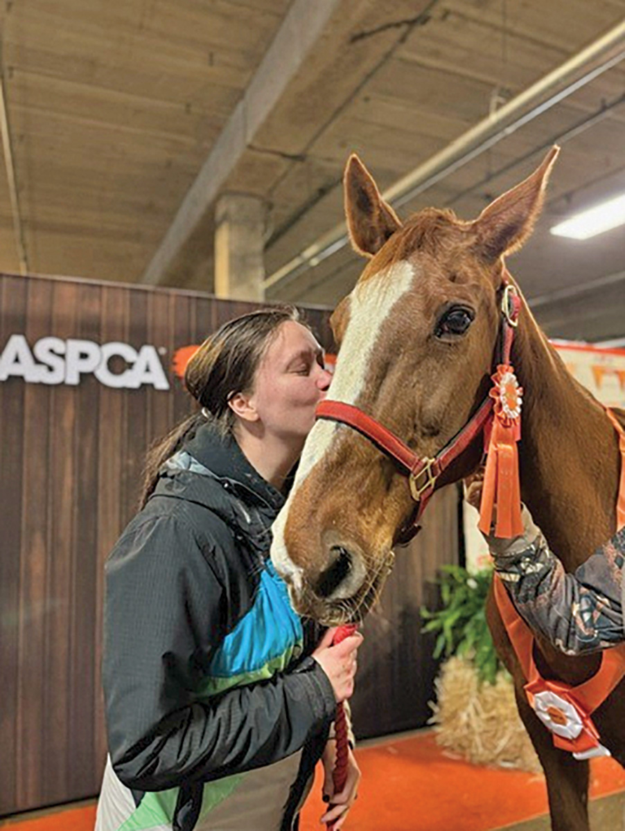 A girl kisses the horse she's just adopted at the Adoption Affaire at Equine Affaire.