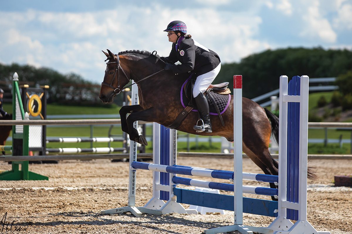 An equestrian jumping her horse