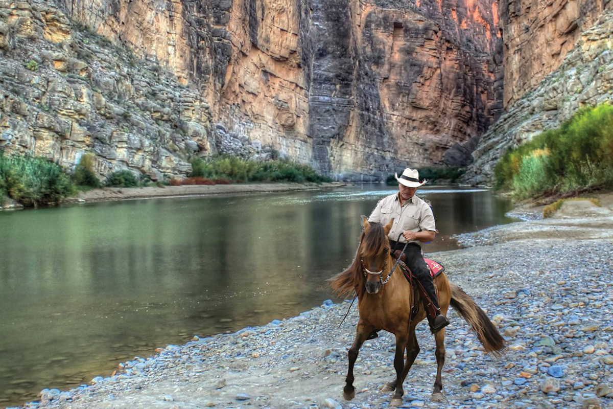 A man riding a Paso Fino horse on a mountain trail