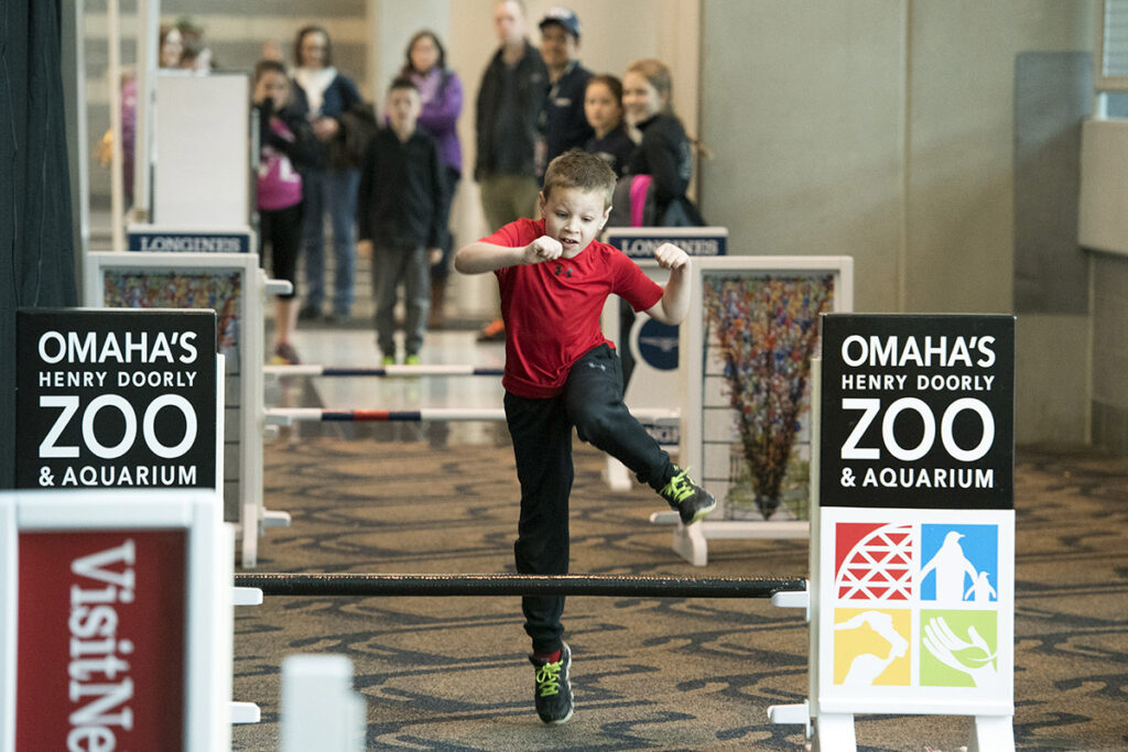 A kid jumps over a mock jumping course