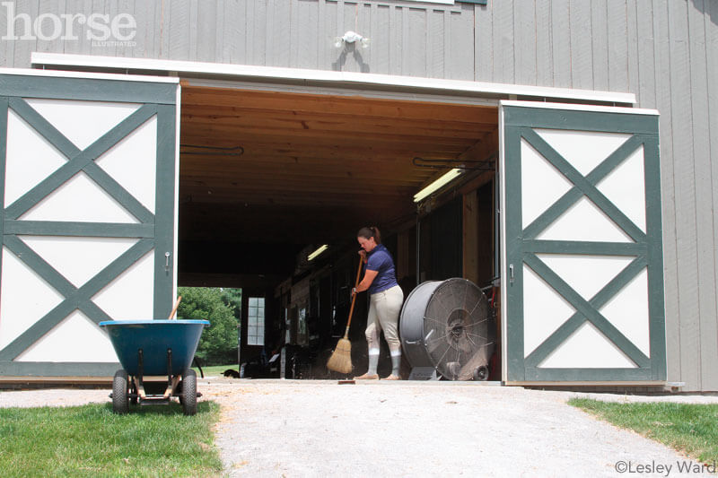 An equestrian cleaning the stable