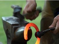 Nominations of exceptional farriers sought for 2013 Summit Achievement Award farrier shaping a hot horse shoe on an anvil