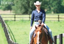 Western horse and rider riding along a fenceline