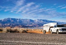 Truck with horse trailer parked on the side of the road with mountains in the background