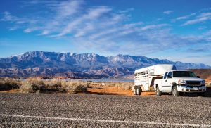 Truck with horse trailer parked on the side of the road with mountains in the background