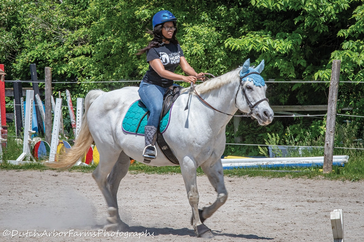 A young girl trotting a gray mare.