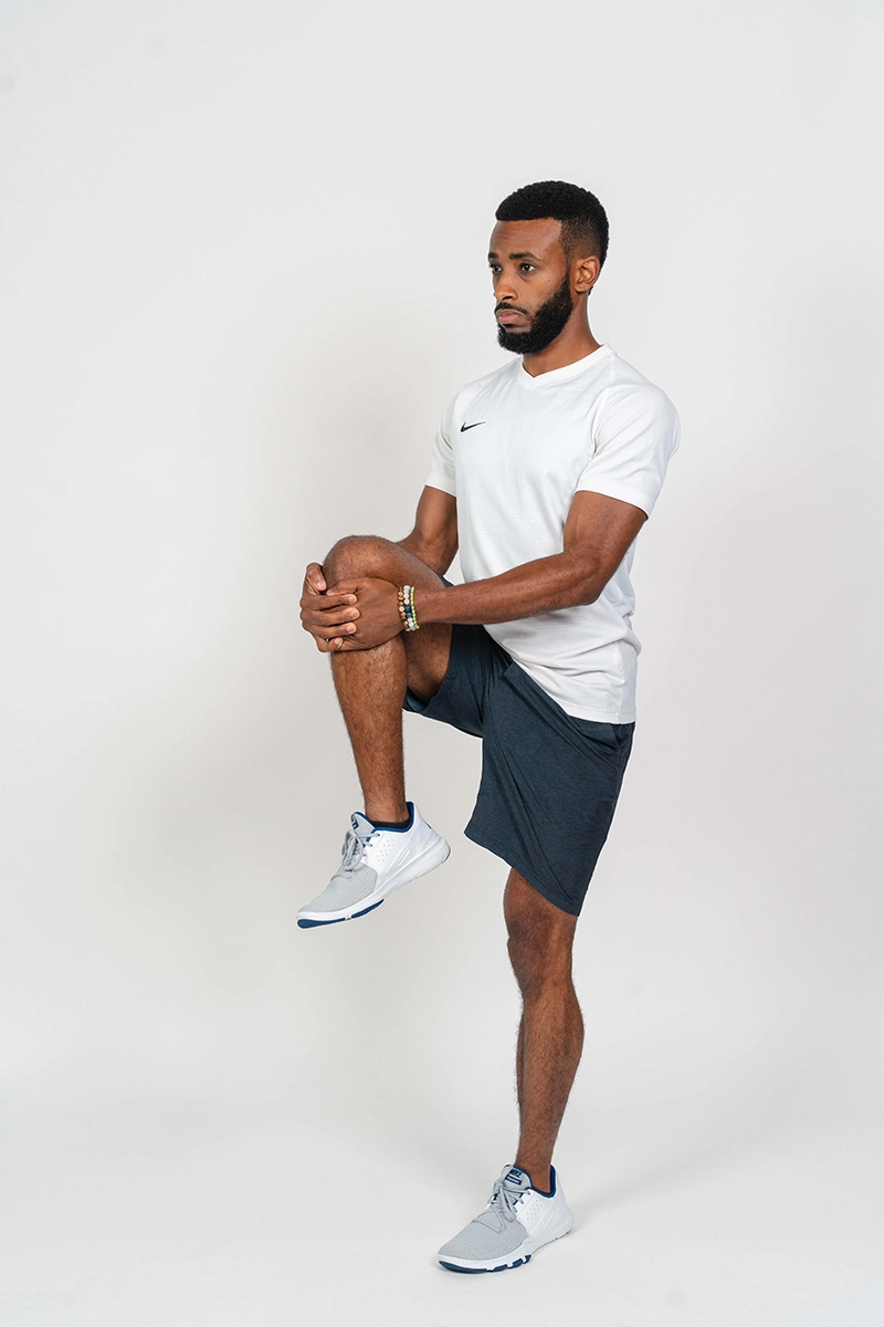 Ifa demonstrating the standing knee hug, one of the key mobility exercises for equestrians.