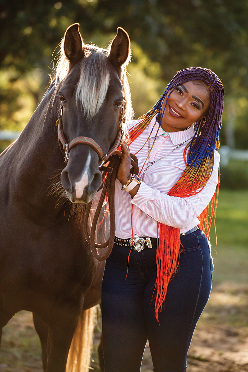 A woman smiles in a portrait with a horse