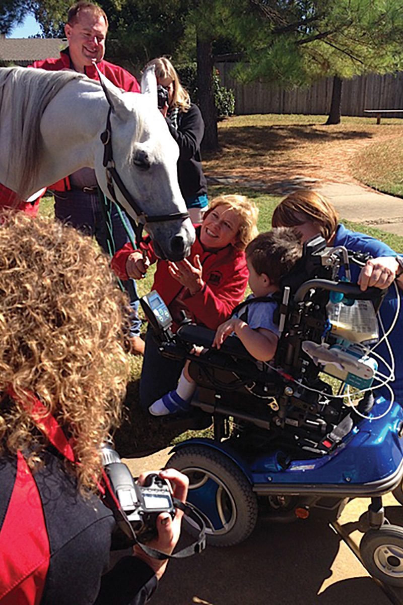 Mary Trowbridge, founder of the Arabian Horsemen’s Distress Fund, interacts with a horse and child