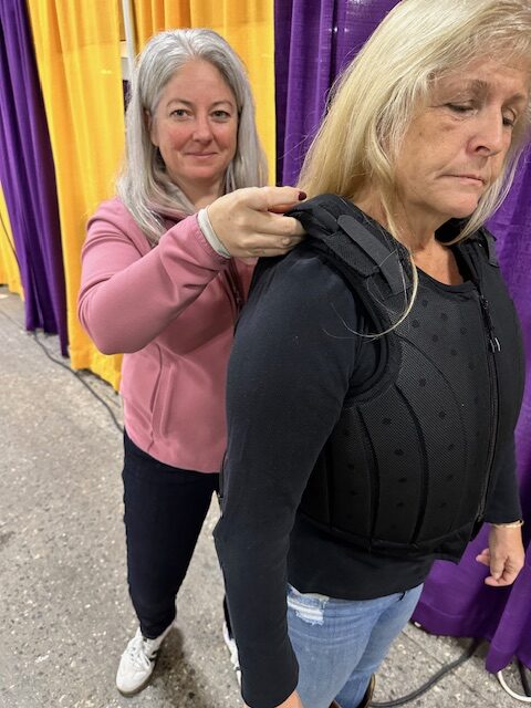 Kimberly Chick, a BETA-certified helmet and safety vest fitter, helps a rider properly fit a safety vest.