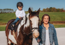 Horse trainer Brynne with her baby son on her horse at the barn
