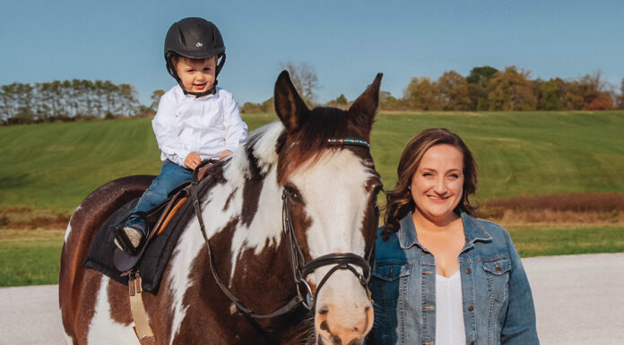 Horse trainer Brynne with her baby son on her horse at the barn