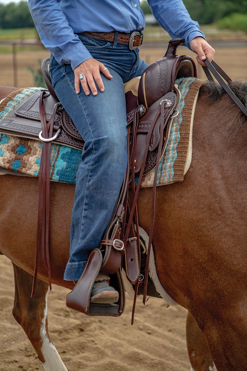 A rider's legs in a Western stirrup.