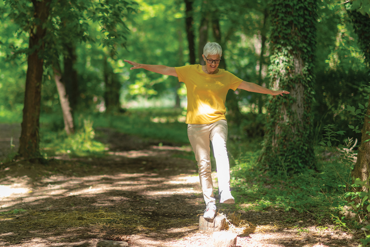 An older woman exercising in the forest.