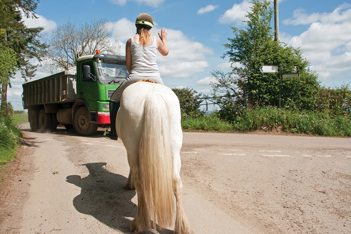 An equestrian indicating for a truck to slow down