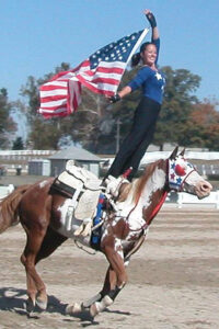 Miko McFarland carries the American flag at the World Equestrian games. She has made trick riding her career.