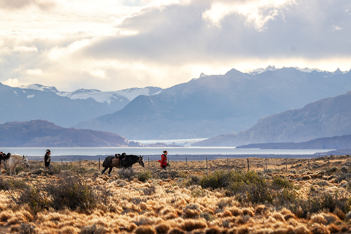 Gaucho Derby riders leading their horses through some tricky ground against a stunning Patagonia backdrop