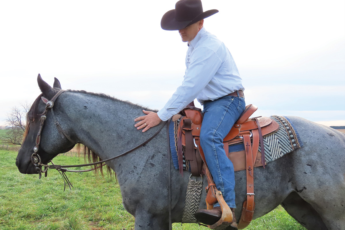 Jason Irwin pets a blue roan while riding