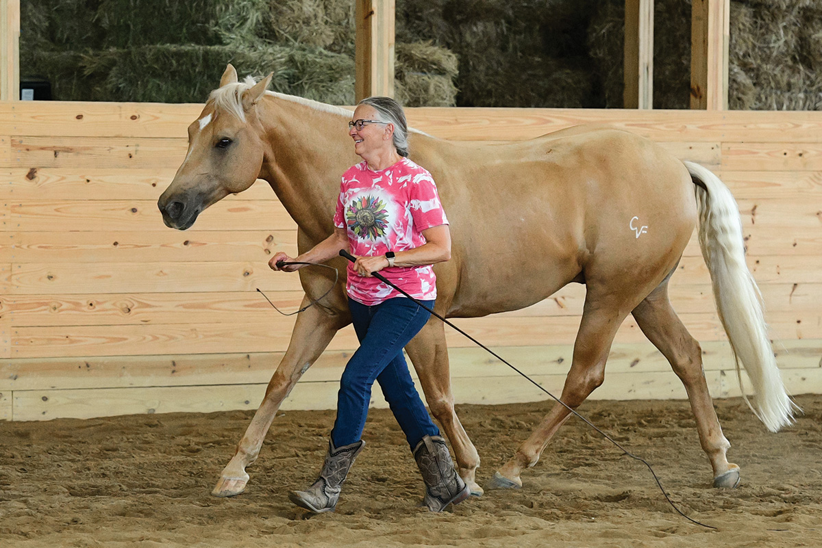 A liberty work student trots with a palomino horse