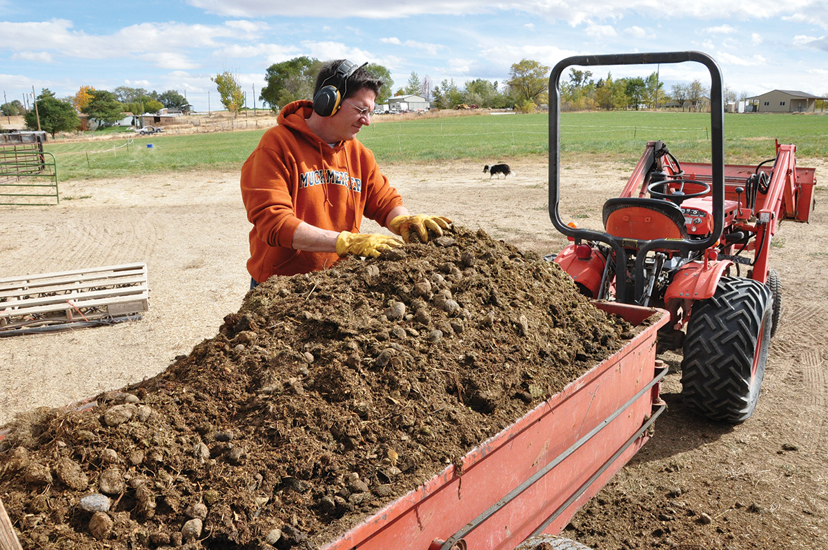 A man working on a spread of compost for spring pasture maintenance