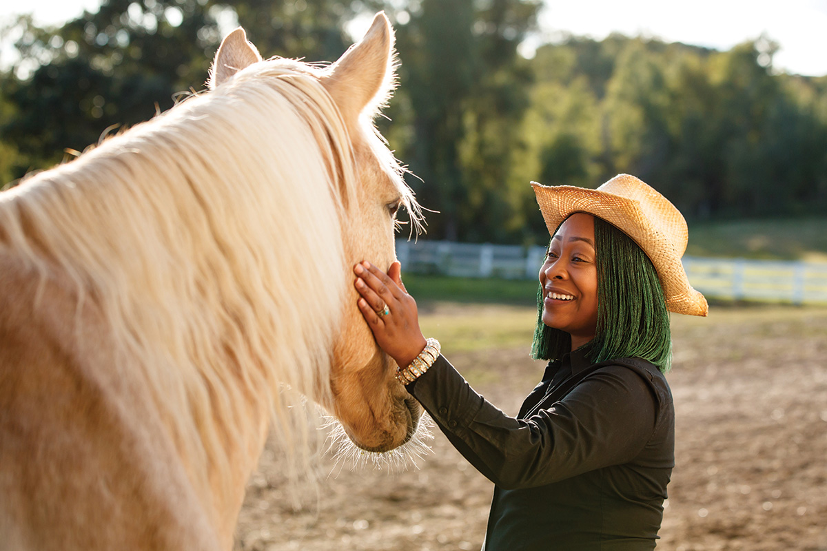 A woman pets a palomino horse