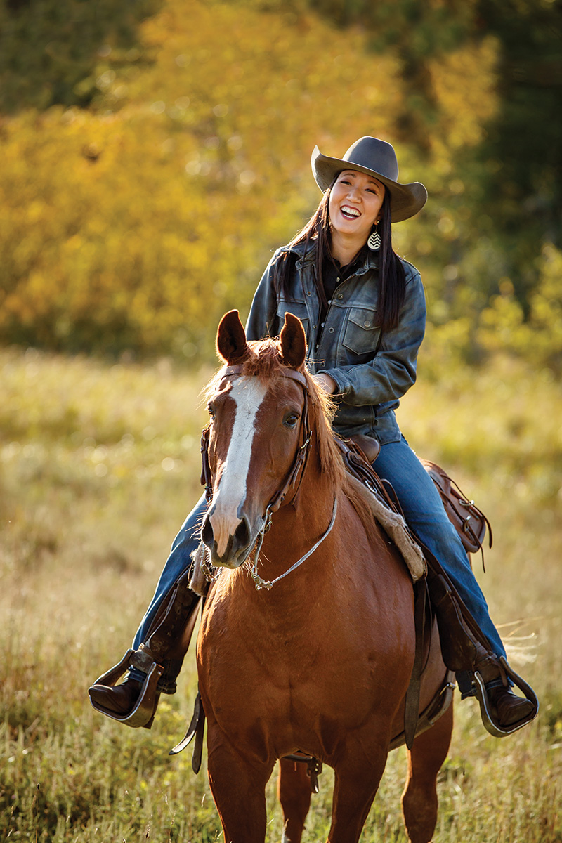 A cowgirl laughing on horseback