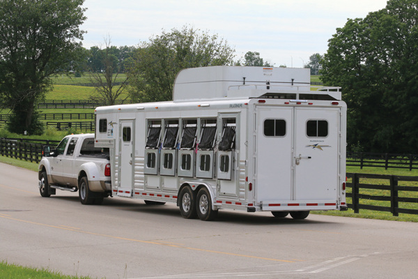 A large trailer going down a farm driveway