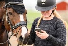 An equestrian checks her phone