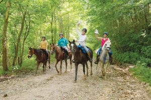 Mounted orienteering riders showing map and clue sheet.