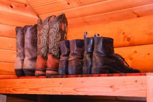 Boots on a shelf in clean tack room.