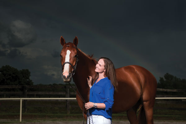 Woman standing with horse against night sky.